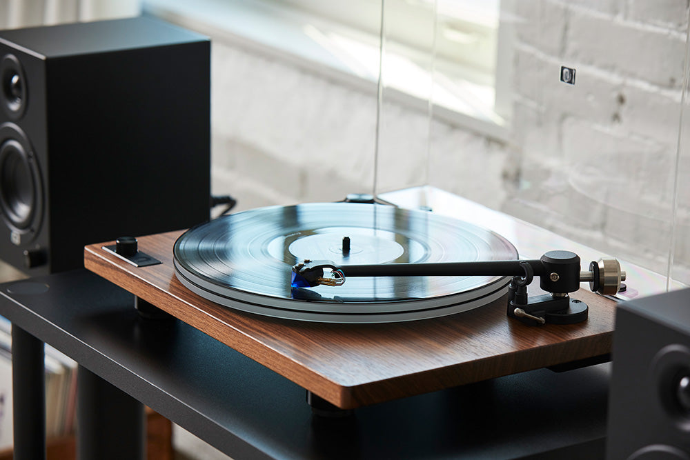 Walnut Orbit Theory with Black Ethos Powered Speakers on a black console